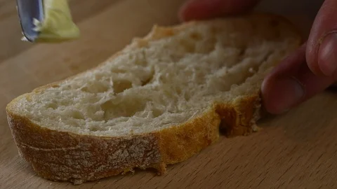 Man spreads butter on bread with a knife Stock Footage 123280946