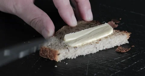 Man spreads butter on bread with a knife Stock Footage 145178646