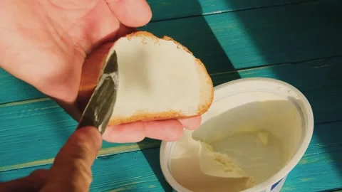 A man spreads cheese on a piece of bread with a knife Stock-Footage 245647061