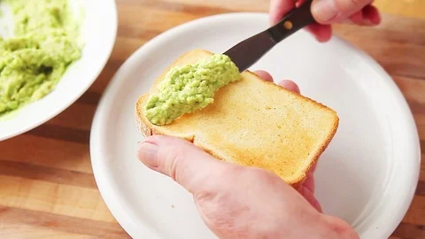 Man spreads mashed avocado on toast Stock Footage 77172198