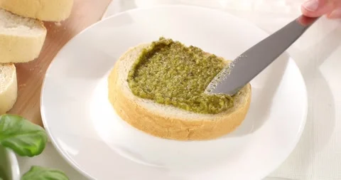 Man spreads pesto sauce on bread with a knife. close-up. angle view. Stock Footage 242499200