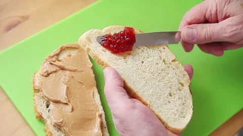 Man spreads strawberry jam on bread Stock Footage 76091673