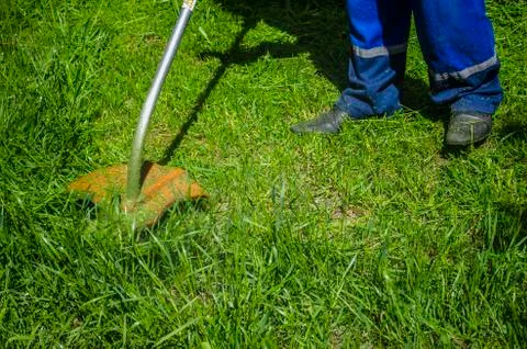 Man in the spring mows a tall grass with an electric oblique Stock Photos