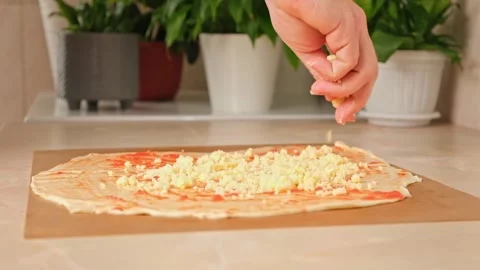 A man sprinkles mozzarella cheese on layer of yeast dough, basis for pizza Stock Footage 244803692