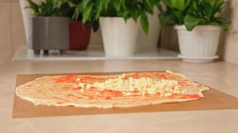 A man sprinkles mozzarella cheese on layer of yeast dough, basis for pizza Stock Footage 245208764