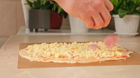 A man sprinkles mozzarella cheese on layer of yeast dough, basis for pizza Stock Footage 246641265
