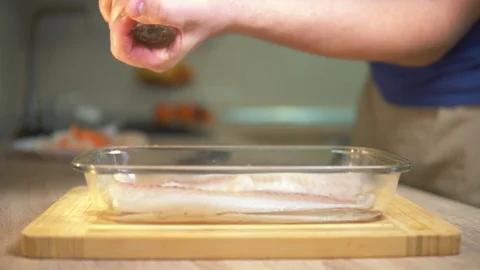 Man sprinkles pepper fish. Cooking fish Stock Footage 101552666