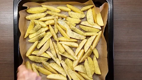 A man sprinkles spices, raw potatoes on protvin. The view from the top. Stock Footage 128839092