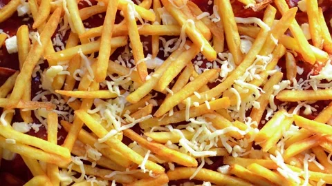 Man sprinkling fresh cheese on top of French fries spread over a pizza Stock Footage 292453335