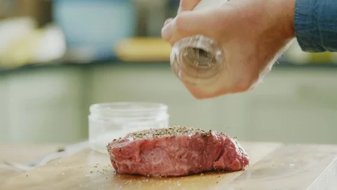 Man Sprinkling Pepper Over Raw Meat On Cutting Board Stock Footage 86070821