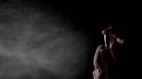 Man sprinkling perfume at the camera. Super slow motion low key video Stock Footage 60034197