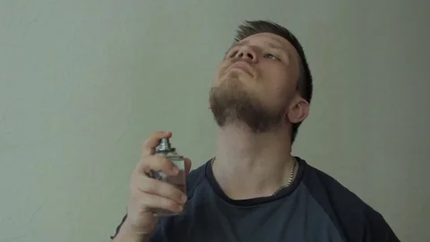 Man sprinkling perfume on his neck, than sniffing scent. Видео 77324789