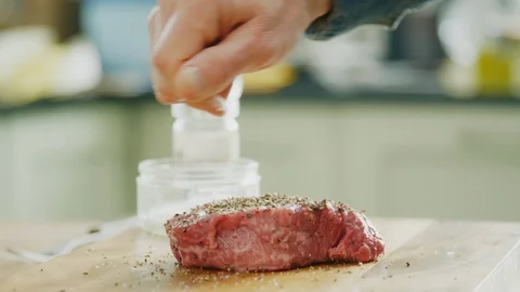 Man Sprinkling Salt Over Raw Meat On Cutting Board Stock Footage 86070848