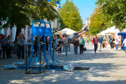 A man in the square does gymnastic exercises on uneven bars and a crossbar. D Foto stock