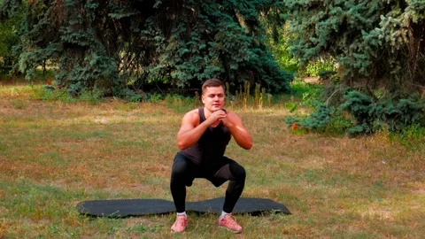 Man squat outdoor on air. Muscular athlete squatting outside Stock Footage