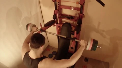 A Man Squats With a Barbell About Swedish Wall in the Room Stock Footage 62476052