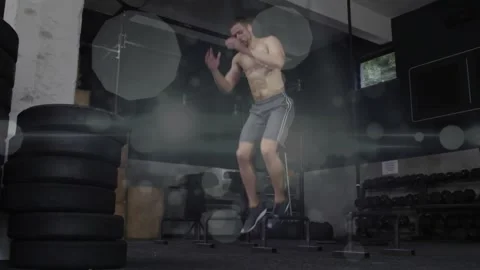 Man squatting exploding, doing plyo jumps in fitness near tires, bokeh obscuring 動画素材 330462525
