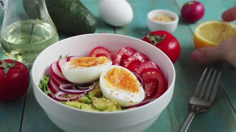Man squeeze lemon juice on fresh salad with avocado  egg tomatoes radish arugula Stock Footage 106512002