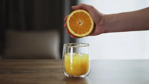 Man squeezes fresh orange juice into a glass. vitamin C, antioxidants Stock Footage 300310070