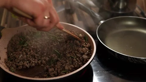 Man squeezes garlic with a garlic press into a pan with minced meat and mixes it Stock Footage 269623372