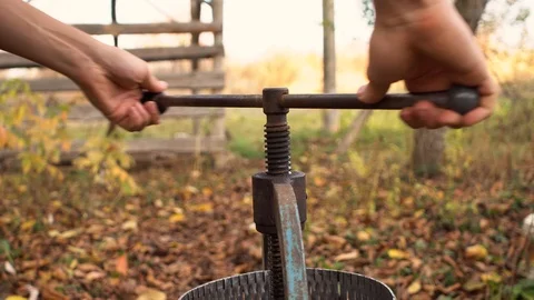 A man squeezes juice using an old press, twisting the handle Stock Footage 119712576