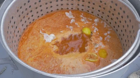 Man Squeezes Lemons into a Large Pot of Spicy Cajun Broth at a Crawfish Boil Stock Footage 74971708