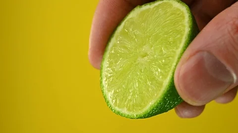 Man squeezes lime on a yellow background Stock Footage 121521063