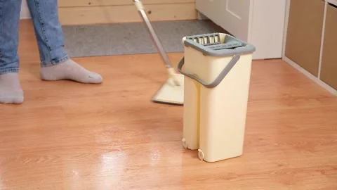 A man squeezes a mop into a bucket and washes the floor. Husband housekeeping Stock Footage 239447952