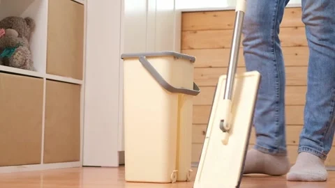 A man squeezes a mop into a bucket and washes the floor. Husband housekeeping Stock Footage 239448147