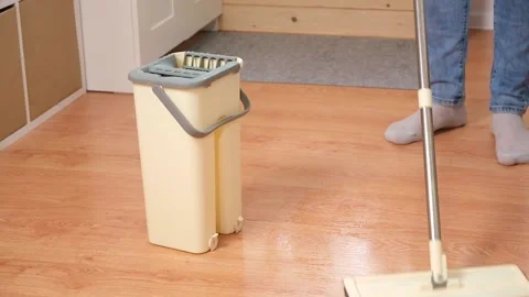 A man squeezes a mop into a bucket and washes the floor. Husband housekeeping Stock Footage 239816906