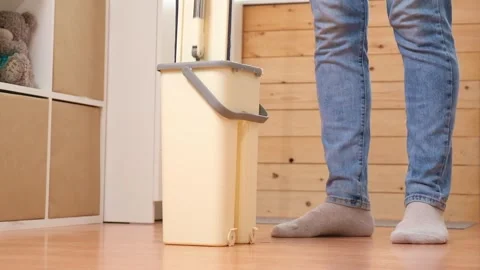 A man squeezes a mop into a bucket and washes the floor. Husband housekeeping Stock Footage 240396381