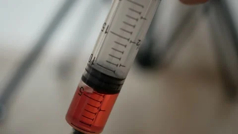 Man squeezes out a syringe with red liquid Stock Footage 147455452