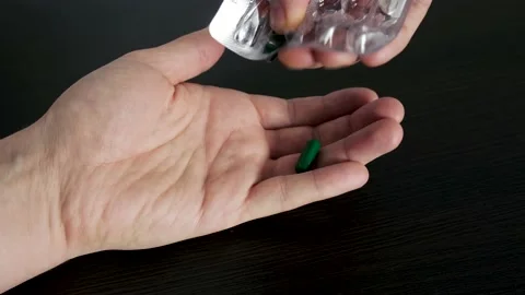 A man squeezes a pill from a blister on his hand. The topic of health care, trea Stock Footage 232148304