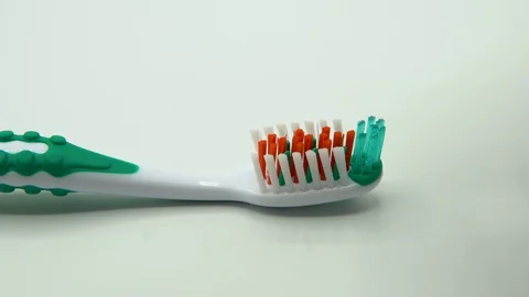 A man squeezes a toothpaste onto the colorful bristles of a plastic toothbrush. Stock Footage 128605350