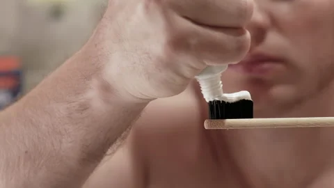 Man squeezes toothpaste onto a toothbrush in the bathroom Stock Footage 212049059