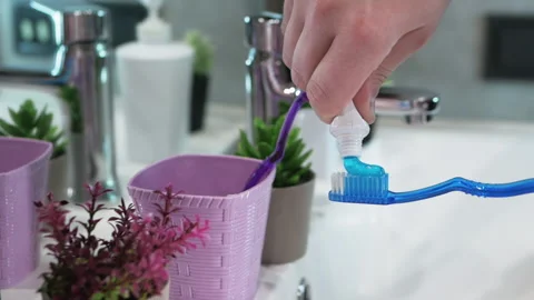 A man squeezes toothpaste onto a toothbrush in a bathroom. Dental care Stock Footage 212804209