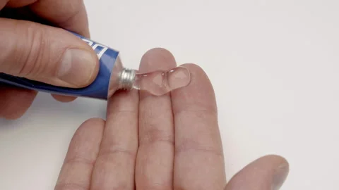 A man squeezes a transparent medical gel from a tube and rubs himself in a sore  Stock Footage