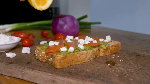 Man squeezing lemon over avocado salmon toast Stock Footage 100040366