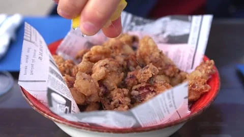 Man squeezing lemon over  Chipirones fritos (Fried baby squid) Stock Footage 261418046