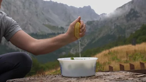Man squeezing lemon to salad in a backyard with mountain background. Slow motion Stockbeeldmateriaal 220058383