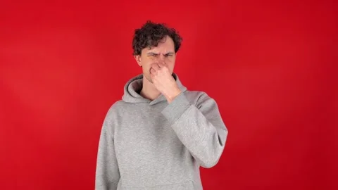 Man squeezing nose fingers, waves hand in front reacting gross, smelly odor. Stock Footage 304749741