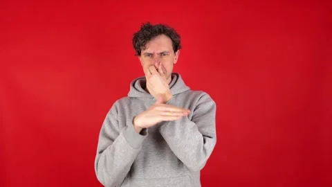 Man squeezing nose fingers, waves hand in front reacting gross, smelly odor Stockbeeldmateriaal 304749780