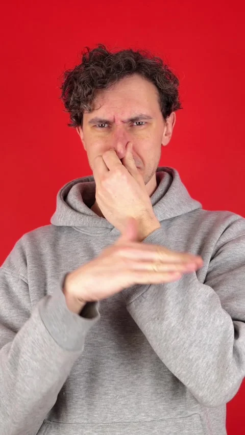 Man squeezing nose fingers, waves hand in front reacting gross, smelly odor 動画素材 304761866