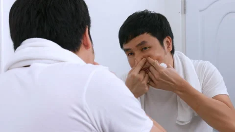 Man squeezing a pimple in the bathroom mirror Stock Footage 153703378