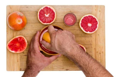 Man squeezing ruby grapefruit halves Stock Photos