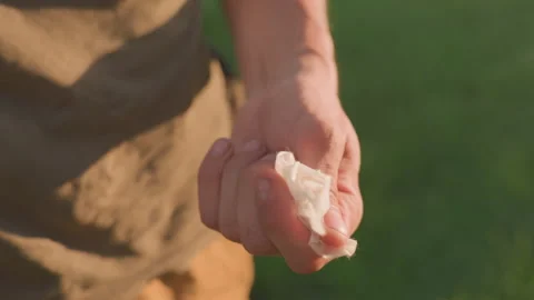 Man Squeezing Tissue, Person With Tense Grip On Tissue In Sunlight Park Setting 스톡 동영상 329531297