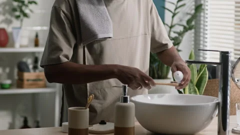 Man Squeezing Toothpaste on Toothbrush by Ceramic White Sink in Bathroom Stock Footage 291281436