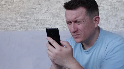 The man is squinting looking into the phone. The concept of poor eyesight Vídeo Stock 128486068
