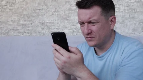 The man is squinting looking into the phone. The concept of poor eyesight Vídeo Stock 129036406