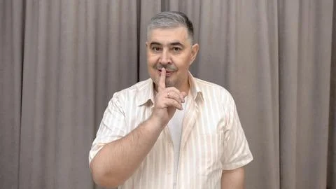 Man Squinting Mischievously and Gesturing "Shh" with Finger to Lips Stock Photos